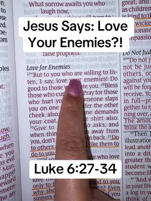 A close-up shot of an open Bible. A finger with a pink nail points towards the highlighted text. A text overlay reads 'Jesus Says: Love Your Enemies?!' with 'Luke 6:27-34' below it.