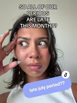 A young woman with dark hair and a nose ring is shown in a close-up. She's looking off to the side with a concerned expression. Overlay text at the top says, 'SO ALL OF OUR PERIODS ARE LATE THIS MONTH??' and a colored, oval-shaped text bubble at the bottom reads 'late july period??'.