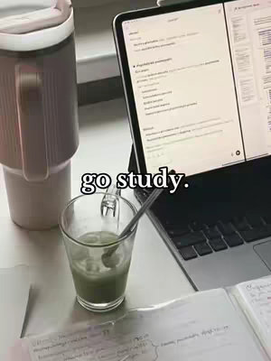 An image showing a workspace with a laptop, a drink, and study materials. The laptop screen displays text, and handwritten notes are visible, suggesting a study session. A drink with a straw is in a glass, and a stainless steel thermal bottle is next to it.