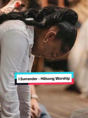 A person, likely a woman, is bowing their head, possibly in prayer or deep emotion, with a white shirt and a blurred background. The image has a teal and red bar with the text 'I Surrender - Hillsong Worship'.