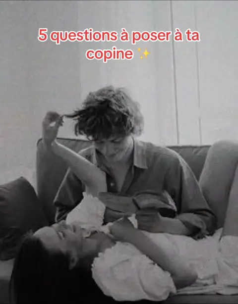 A black and white image of a couple in a loving embrace on a couch. The man is holding her hair. The hook text, '5 questions à poser à ta copine' is written in red.