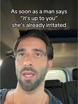 A man in a car looks up with an open mouth and a questioning expression. Text overlays the image, with the background suggesting a daytime setting.