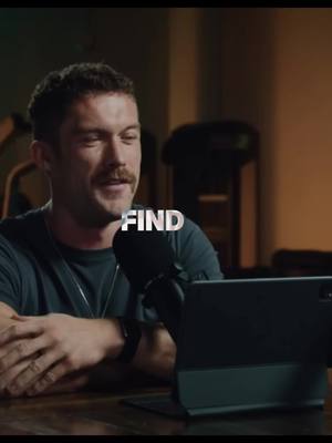 A man with a mustache is speaking into a microphone. The word "FIND" is overlaid on the image near the man's head. Behind him is an out-of-focus background with what looks like a workout machine.
