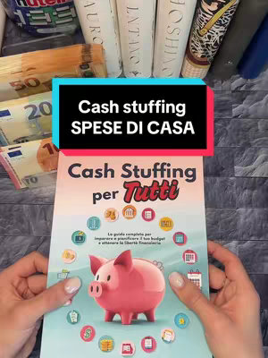 The cover image features a person holding a book titled "Cash Stuffing per Tutti" with a piggy bank illustration on the cover. The person is holding the book with both hands, with several banknotes visible to the side of the book, which suggest that the video content is about budgeting and finance. Above the book is a text overlay that explains "Cash stuffing SPESE DI CASA".