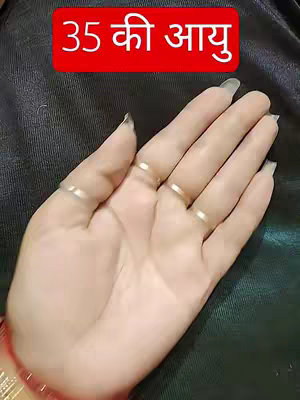 A close-up of a hand with multiple rings on the fingers. The background is a dark, possibly fabric-like material. The hand appears to be fair-skinned and manicured. A red rectangular text overlay displays text in a different language.
