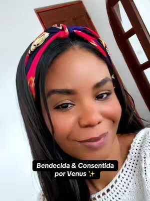 A selfie-style shot featuring a woman with dark hair and a headband. The background seems to be inside a home. The woman appears to be smiling and looking towards the camera, and a text overlay is present at the bottom.