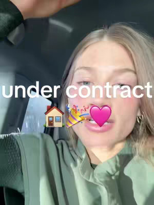 The cover image is a selfie-style shot featuring a young woman with fair skin and blonde hair, centered in the frame. She appears to be in a car, with the interior visible in the background. The overlay features the text "under contract" in a sans-serif font, along with emoji of a house, a party horn and a pink heart placed near the woman's mouth. She is looking toward the camera.