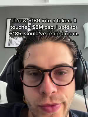 A man with glasses is centered in the frame, with text overlayed above him. He's wearing headphones and a dark shirt. The background is a light gray wall with a black framed photo. The text is white and easy to read.