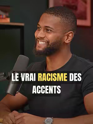 The cover image features a man speaking. The man has short, dark hair and a beard, and he is wearing a black t-shirt. In the background are out-of-focus elements, including a dark wall and potentially a frame. The text overlay reads "LE VRAI RACISME DES ACCENTS" in a bold, condensed, white font with a yellow background.
