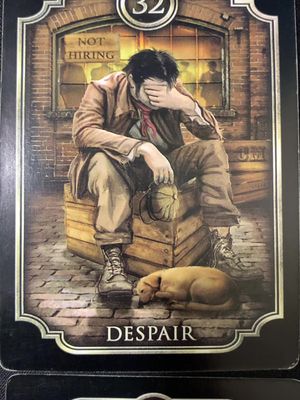 An illustration of a distressed man seated atop a wooden box on a stone-paved street. He covers his face with his hand, expressing despair. A dog lies curled up at his feet. The backdrop features a building with a 'NOT HIRING' sign. The overall tone is somber and melancholic, likely related to the tarot theme and the card's definition.