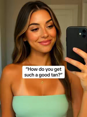A woman is taking a selfie with her smartphone, her face angled slightly towards the camera. She has long, wavy, light-brown hair and is wearing makeup. The woman is wearing a light green, strapless top, revealing a tan line on her chest. A white text box is placed on the bottom of the image with the text overlayed on it. Behind her is a plain white wall.