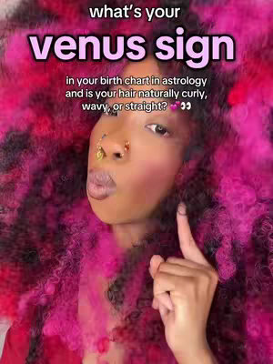 A selfie-style image featuring a young woman with vibrant pink and black curly hair, a bold makeup look with prominent blush, multiple face piercings, and a finger pointed upwards. Overlayed text in a stylized font poses a question about venus sign and hair type. The background is a mix of black and pink that complements the color of the hair, creating a visually striking and attention-grabbing composition.
