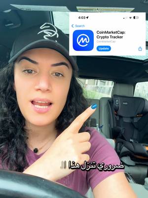 A woman in a car is pointing to the screen of her phone showing a CoinMarketCap app icon. Behind her is a car seat.