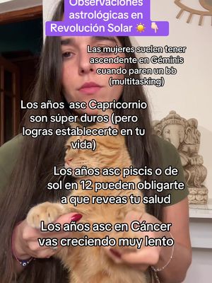 A woman with long dark hair holds a ginger cat in front of her. The background includes parts of her room with a statue and an intricate design. Text overlays cover parts of the image.