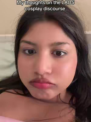 The cover image is a close-up selfie of a young woman with dark hair and fair skin. The top of the frame has the overlaid text, "My thoughts on the LADS cosplay discourse". The woman has a neutral expression, and she is wearing a light pink top. The lighting is natural, and the background is out of focus.