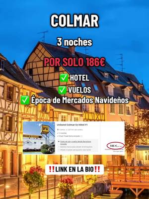 The image showcases a picturesque European town with colorful buildings, a clear blue sky, and text overlayed to promote travel deals. The buildings have a classic architectural style, with half-timbered walls. The text offers a travel offer for the destination Colmar, including the duration and price.