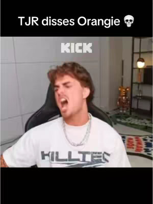 The image shows a young man with light brown hair, wearing a white t-shirt, and seated in a chair. He has an open mouth as if shouting or singing. Text overlay is placed at the top of the image, with another below.