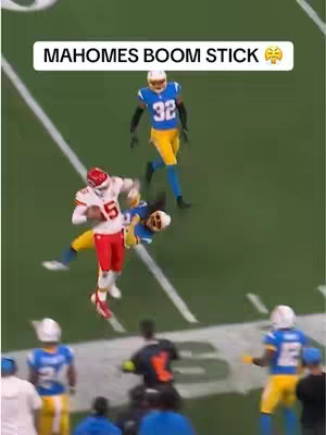 The image captures a moment from an NFL game, focusing on Kansas City Chiefs' quarterback Patrick Mahomes (wearing jersey #15) being tackled by players from the opposing team. The scene is set on a green field with white yard lines. The color palette primarily includes red, white, and yellow for the Chiefs and blue and yellow for the opposing team, creating a dynamic and action-packed composition.