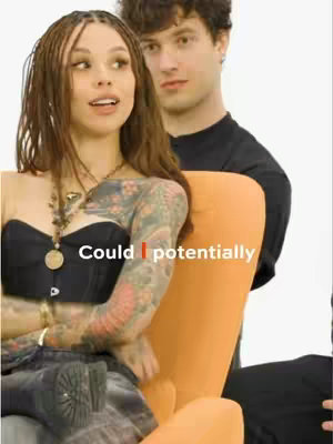 The cover image features a woman with braided hair looking off to the side, and a man behind her. The woman is sitting in an orange chair, and has colorful tattoo sleeves.