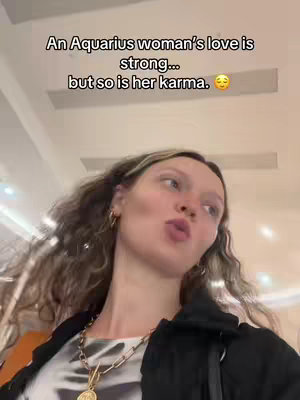 A video cover shows a woman with wavy, light-brown hair, looking at the camera with a slight pursed-lip expression. She is wearing a top with a distinctive pattern and a necklace with a circular charm. The background is a brightly lit, non-descript interior.