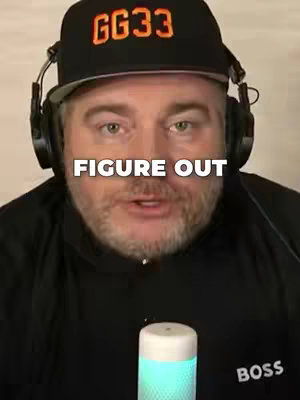 A man is centered in the frame, wearing a black cap with 'GG33' in orange letters, and headphones. The text 'FIGURE OUT' is superimposed in white across his chest. In the lower frame, a cylindrical object with a white top and glowing blue light is visible.