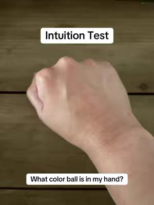 The image shows a hand, presumably the creator's, making a fist. The background is made of wooden planks. There are two text overlays: one reads 'Intuition Test' at the top, and 'What color ball is in my hand?' at the bottom.