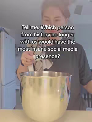 A woman stands in a kitchen holding a whisk above a large mixing bowl. The background includes a white refrigerator and kitchen counter.