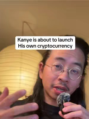 A selfie-style video with a man in the foreground, holding a microphone, with a text overlay and a round, light-colored object in the background. The man is fair-skinned with dark hair, round glasses, and a short beard. He is speaking directly at the camera. Behind him is what appears to be a large, off-white paper lantern, and the background is a warm, neutral color.