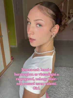 A woman with fair skin, light-colored eyes, and dark hair styled in a half-up bun looks toward the viewer. She wears a white top and a pearl necklace and earring. Text is overlaid in pink.