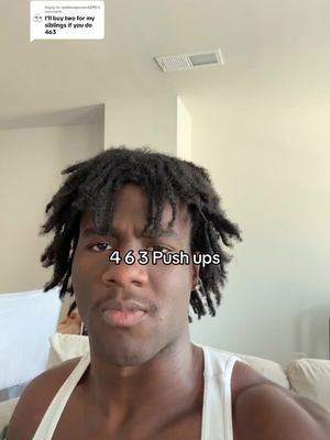 A selfie-style shot featuring a young Black man against a light wall and ceiling. The man has short dreadlocks and is wearing a white tank top. Text overlayed at the bottom of the image reads "463 Push ups".
