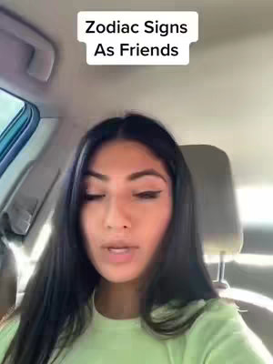 A woman is seated in a car, with a light green shirt. The overhead text states "Zodiac Signs As Friends".