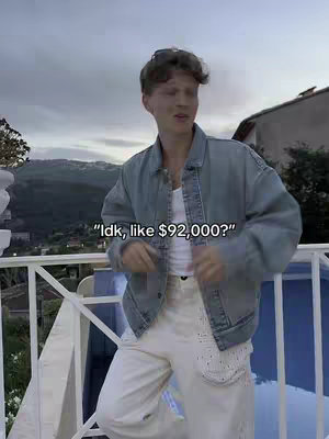 The image features a young man as the central figure, standing on a balcony with a cloudy sky and mountain in the background. He's wearing a denim jacket over a white tank top and off white pants, with sunglasses perched on his head. Text, likely a quote or hook, is overlaid on the image.