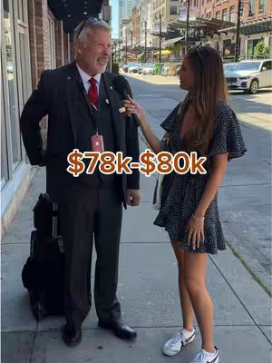 A street interview featuring a man in a suit and the interviewer. The man is holding a microphone while the interviewer speaks. The overlay text indicates a salary range.