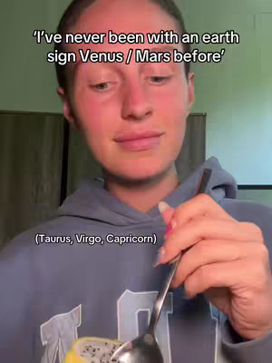 A woman with fair skin wearing a blue hoodie is holding a spoon and a piece of food. The text overlay reads "I've never been with an earth sign Venus / Mars before."