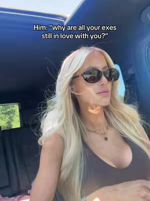 A woman with long, blonde hair and sunglasses is seated in a car. The scene is bright with sunlight, and text overlays the image.