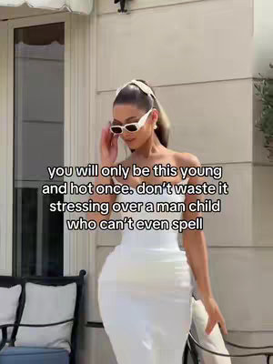 A woman in a white dress and sunglasses holds her sunglasses while posing for the camera. Text is overlaid on the image.