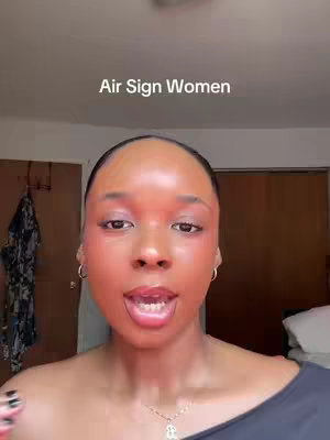 A close up shot of a woman's face with 'Air Sign Women' text overlayed. She is looking at the camera with open mouth. The background includes a closed door and a glimpse of some clothes.