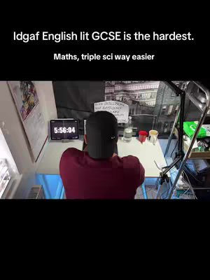 A person is sitting at a desk, facing away from the camera. The person is wearing a black cap and a dark red shirt. On the desk is a tablet displaying a timer, various stationary items, and a sign. Above, text overlayed says, "Idgaf English lit GCSE is the hardest. Maths, triple sci way easier".