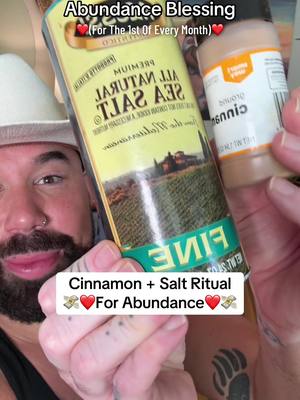 A man with a beard and a white cowboy hat holds up a container of sea salt and a bottle of cinnamon, appearing to be promoting a ritual. Overlay text reads 'Abundance Blessing' and 'Cinnamon + Salt Ritual'.