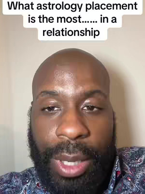The cover image features a close-up of a Black man with a shaved head and a full, dark beard. Above him is a white text overlay with the question, 'What astrology placement is the most ... in a relationship.' The man's expression is serious as he looks into the camera, suggesting he is about to provide an answer or explanation regarding the topic. The lighting suggests a well-lit indoor setting, while a patterned, dark-colored shirt adds a touch of formality.