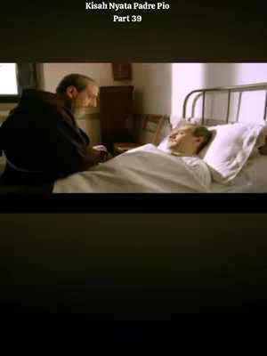 A scene from a film featuring two men. One, in a brown robe, is leaning over a man lying in a bed, who is covered with a white sheet. The setting appears to be a simple room with minimal decor.