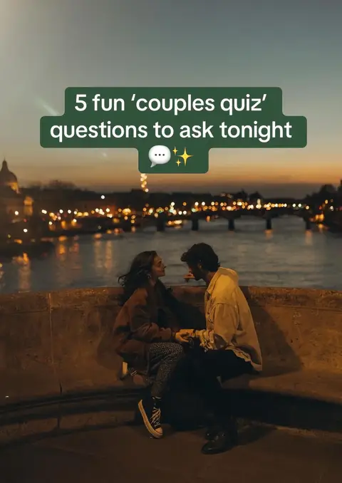 A romantic evening scene on a bridge with two people, a man and a woman, silhouetted against a sunset backdrop. The sky transitions from orange to dark blue, showing a city's lights and a bridge in the distance. The couple is holding hands. Text overlayed on the image reads '5 fun 'couples quiz' questions to ask tonight'.