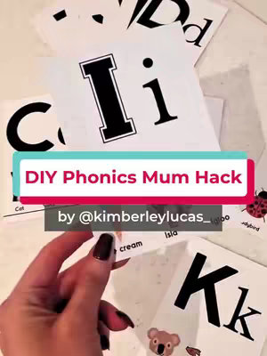 The cover image shows a hand holding a flashcard with the letter 'I' on it, part of a stack of similar cards featuring other letters like 'C', 'D', and 'K'. The background is a light surface, and there is a text overlay that reads 'DIY Phonics Mum Hack'.
