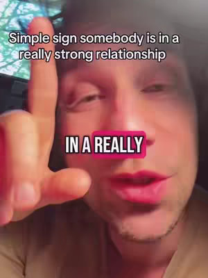 A close-up shot of a man's face with a finger pointing up and text overlays, suggesting a relationship tip. The man has fair skin, short hair, and is speaking with his mouth open. Text overlays include 'Simple sign somebody is in a' and 'IN A REALLY' in a pink box.