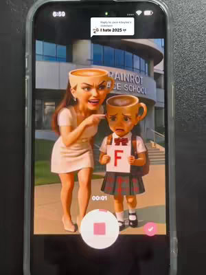The cover image showcases a humorous digital illustration displayed on a phone screen. The foreground features a cartoonish representation of a woman and a child, both with heads resembling coffee cups. The woman is pointing at the child, who is holding a card displaying the letter 'F.' The backdrop suggests a school environment, with a building and green surroundings. The image is framed within the phone's interface, with a recording control and a comment overlayed on top.