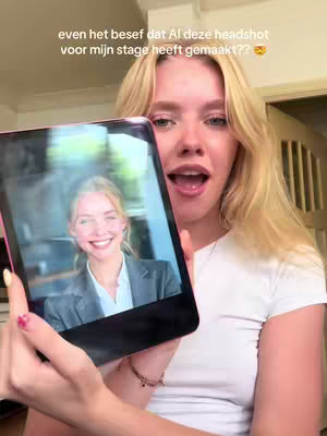 A young woman with blonde hair and a white t-shirt is holding a tablet, displaying a headshot of herself. Her mouth is open in surprise, and in the background is a typical home interior.