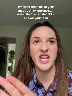 A woman with brown hair and fair skin is looking towards the camera with her mouth wide open. Text is overlaid at the top of the frame. It appears as though she is speaking. The background is blurred, with a glimpse of a room with a door and some greenery. She is wearing a patterned shirt. 