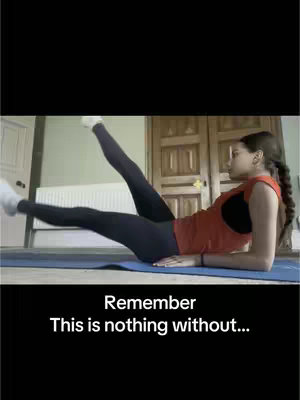 A woman in workout gear is doing an exercise on a blue mat, her legs extended in the air. The background has a wooden door and what appears to be a white radiator.