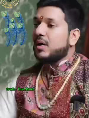 A man in traditional Indian attire is the central figure. He has a round red mark on his forehead. A series of six blue peacock feathers are on the woman's other side . The background is a subtle green pattern, with text, 'Credit - True Shabd' over the white background.