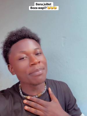 A selfie-style shot with a young Black man, positioned from the chest up, looking towards the camera with a slight smile. He is wearing a black t-shirt and a beaded necklace. The background is a light shade of blue, suggesting an indoor setting. Text overlays at the top of the frame, in a white banner, in white sans-serif font. The overall composition is simple, focusing attention on the man.